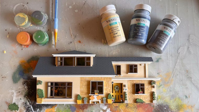 Assembling painted wooden layers into a finished house replica